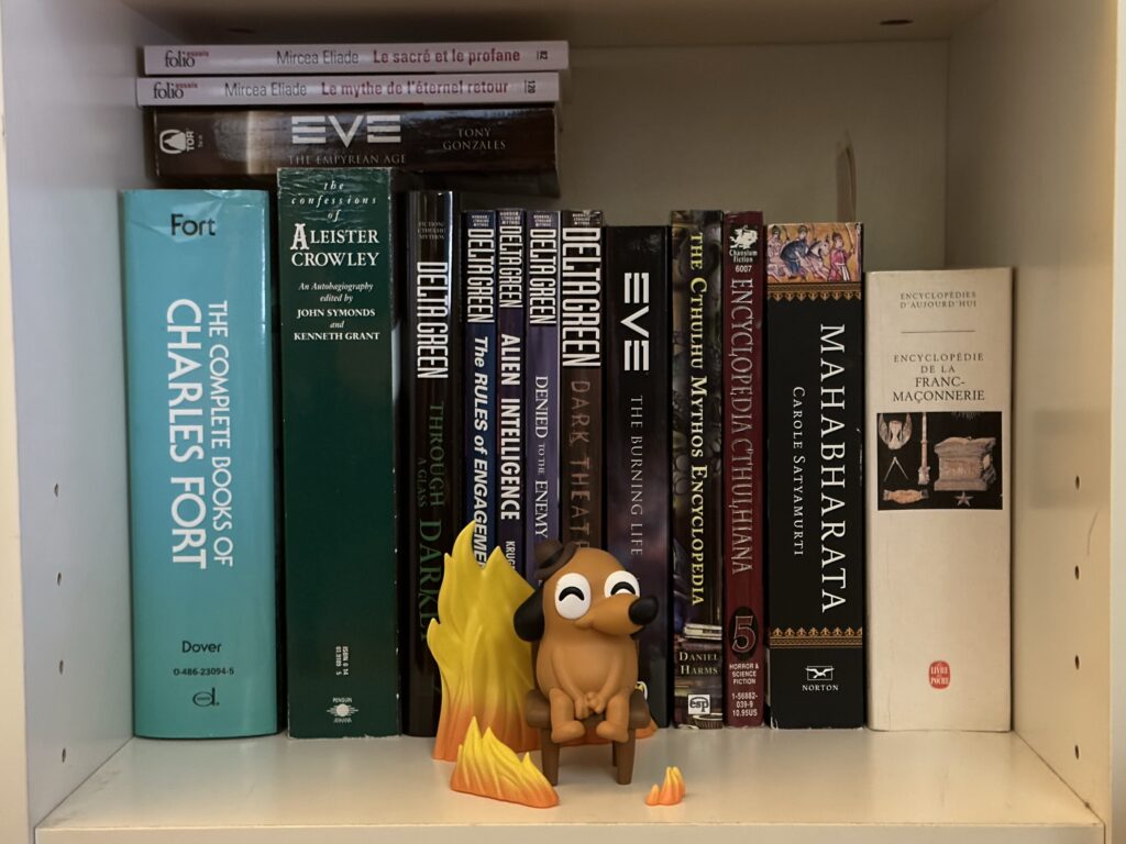 A small vinyl statue of the "This is fine" meme in front of some books
