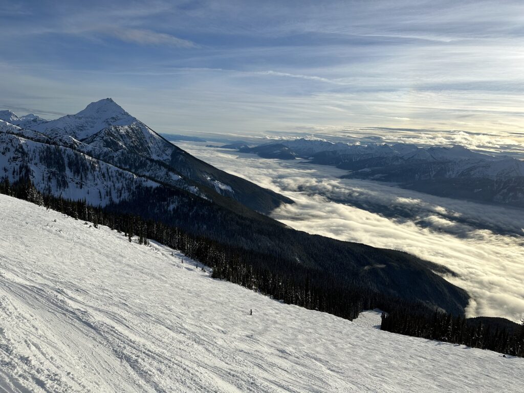 A nice view of the Canadian Rockies with snow covered tops and a valley hidden under a low cloud cover