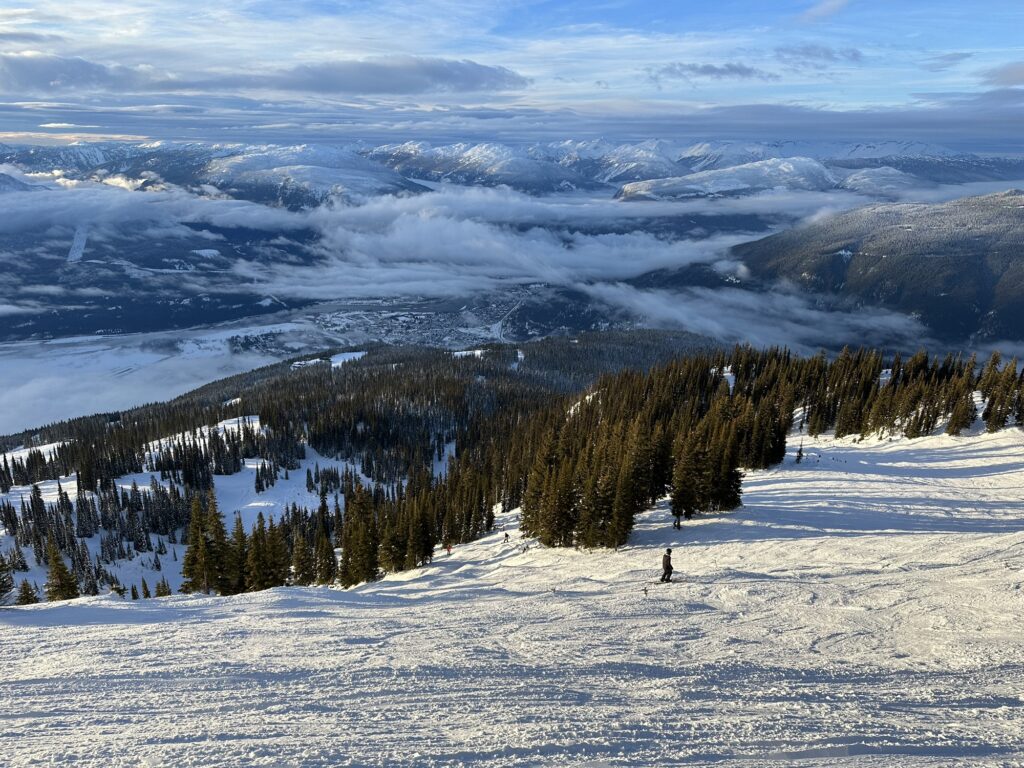 A nice view of the Canadian Rockies with snow covered tops and a valley hidden under a low cloud cover