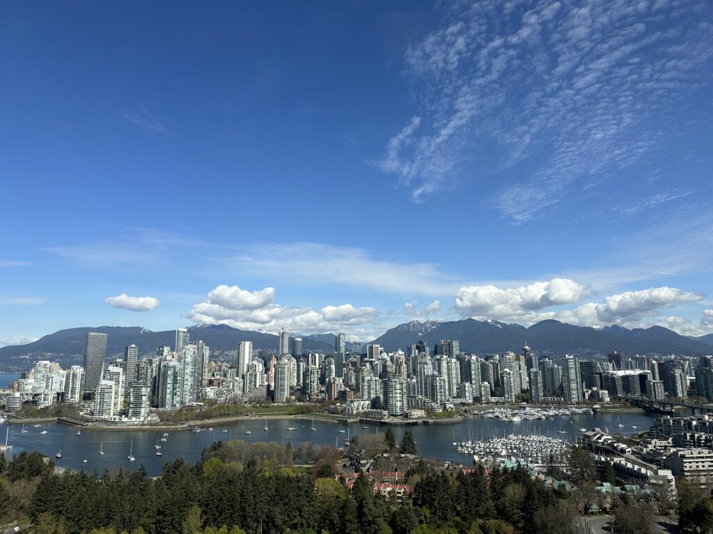 The skyline of Vancouver, BC, with some pretty mountains behind it, and False Creek in the front.
