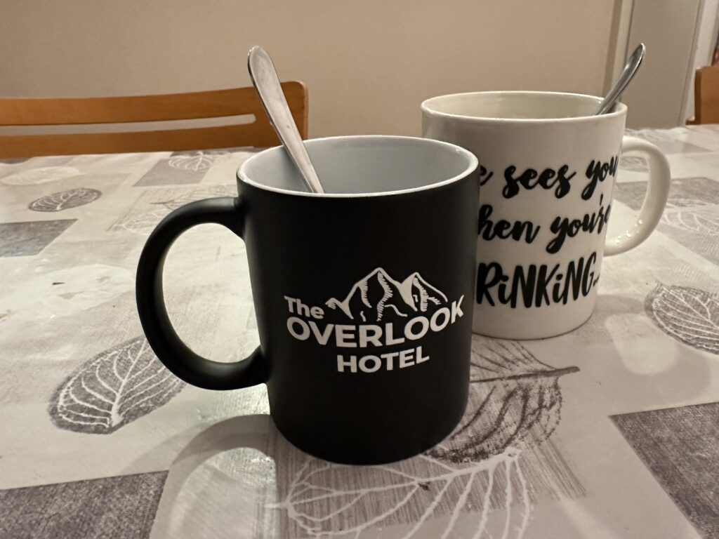 A mug with an "Overlook Hotel" logo. I'm not sure we see any logo in the movie so I don't think this is "canon" by any means.
For fun, the picture also shows my wife's festive mug, with the writing: "He sees you when you're drinking".