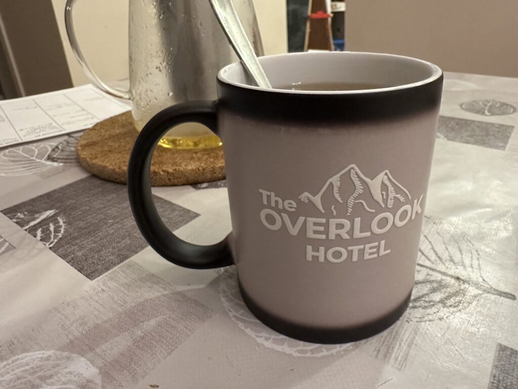 The Overlook Hotel mug with hot tea in it. The black colour of the mug has now turned to grey/beige.