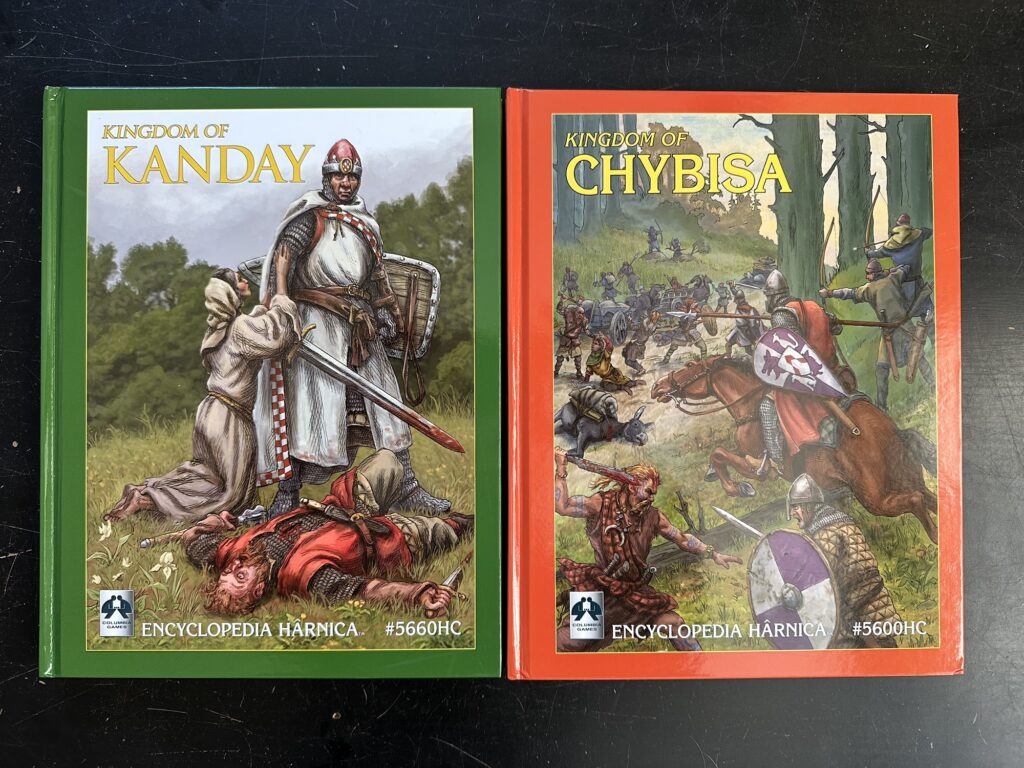 The two hardcovers side by side. 

The Kanday book shows a knight who has just killed what looks like a brigand of some kind and some lady possibly asking for mercy.

The Chybisa book shows a skirmish between the kingdom's army and some neighbouring tribe.