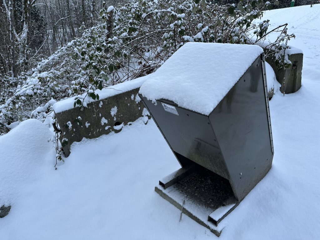 A bear-proof garbage container covered in snow and ice.