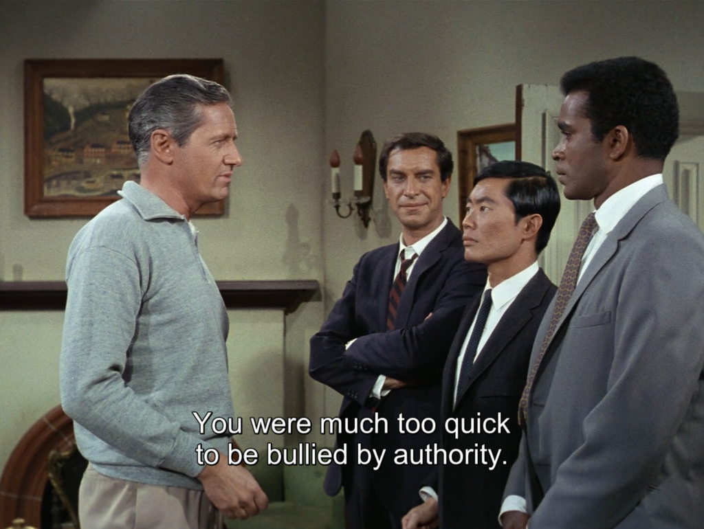 Rollin Hand (Martin Landau), Roger Lee (guest star George Takei), and Barney Collier (Greg Morris) are undercover in a training camp for sleeper agents in the US. They were just fake-arrested by Russians posing as US police, and only Rollin had the sense of protesting arrest, screaming about warrants and civic rights until the police backed off.
Yanosh Passik (Arthur Hill), the mastermind and "US culture specialist" behind this training program, shows up and reprimands Roger and Barney:
"You were much too quick to be bullied by authority"