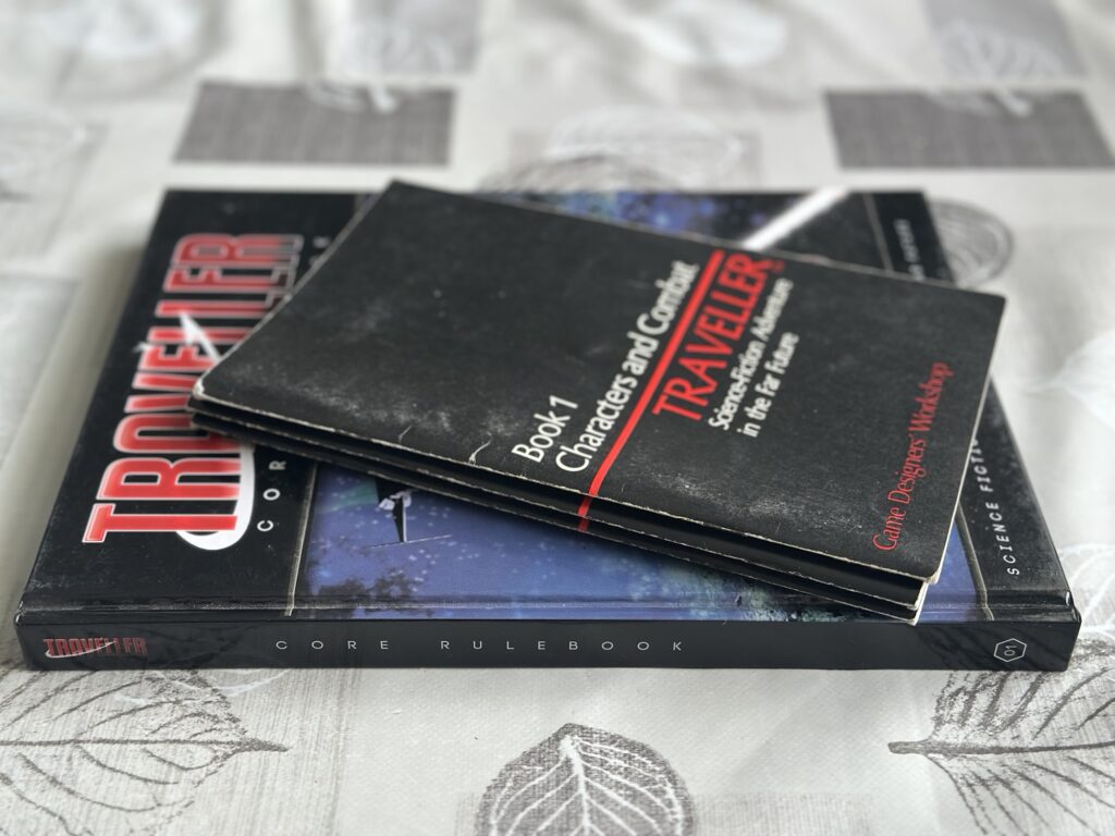 The classic Traveller little black books on top of the Mongoose Second Edition rulebook.