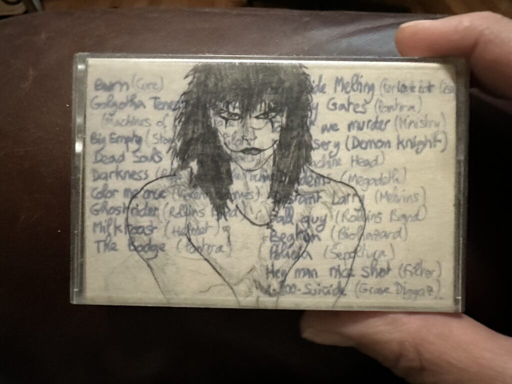 A cassette case with the list of songs from the soundtrack to The Crow, and a shitty drawing (by teenage-me) of the titular character.