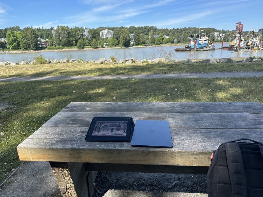 An iPad with a painting in progress, on a picnic table by the shore of the Fraser River in BC, Canada.