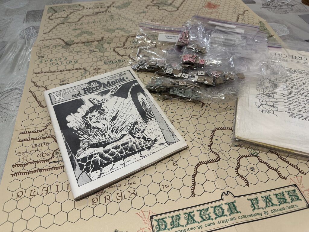 The White Bear & Red Moon board game from 1975, by Greg Stafford. The chits are organized in ziploc bags. The rulebook sits atop the original sepia map of Dragon Pass.