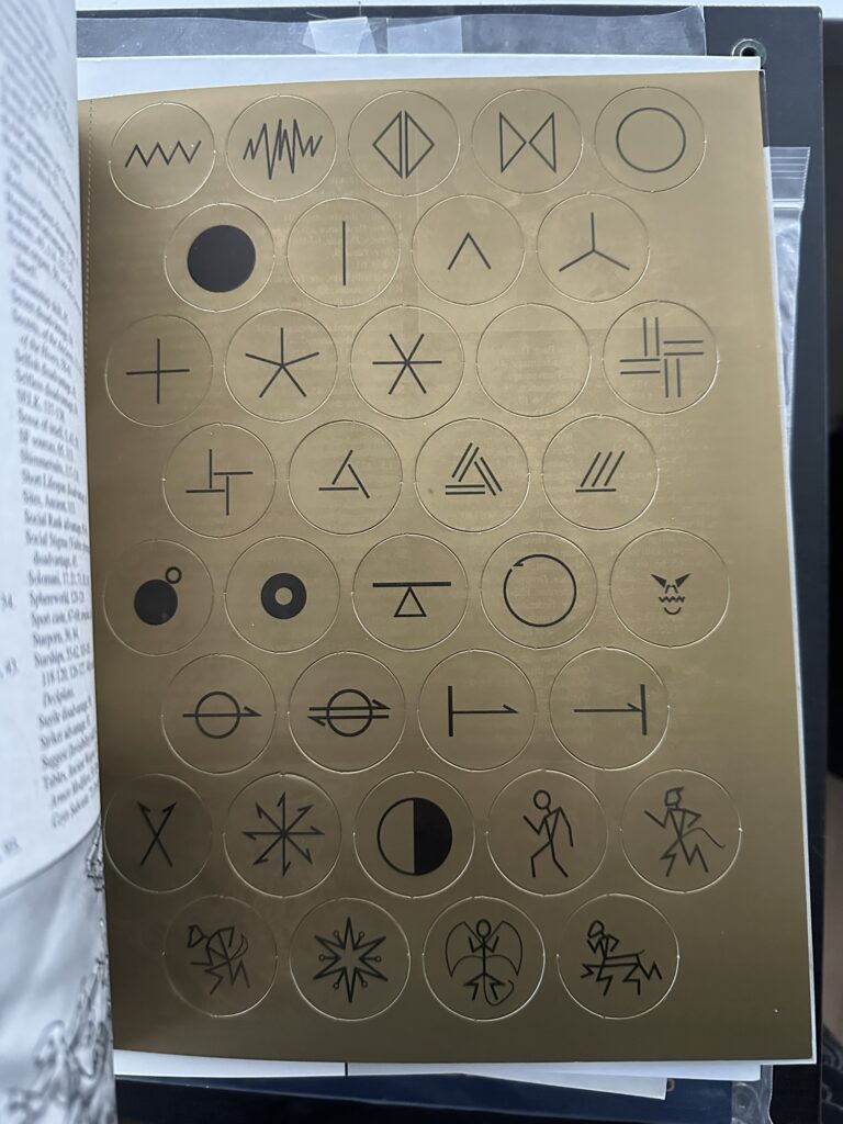 The page of Droyne Coyns. Golden circular tokens with geometric symbols on them.